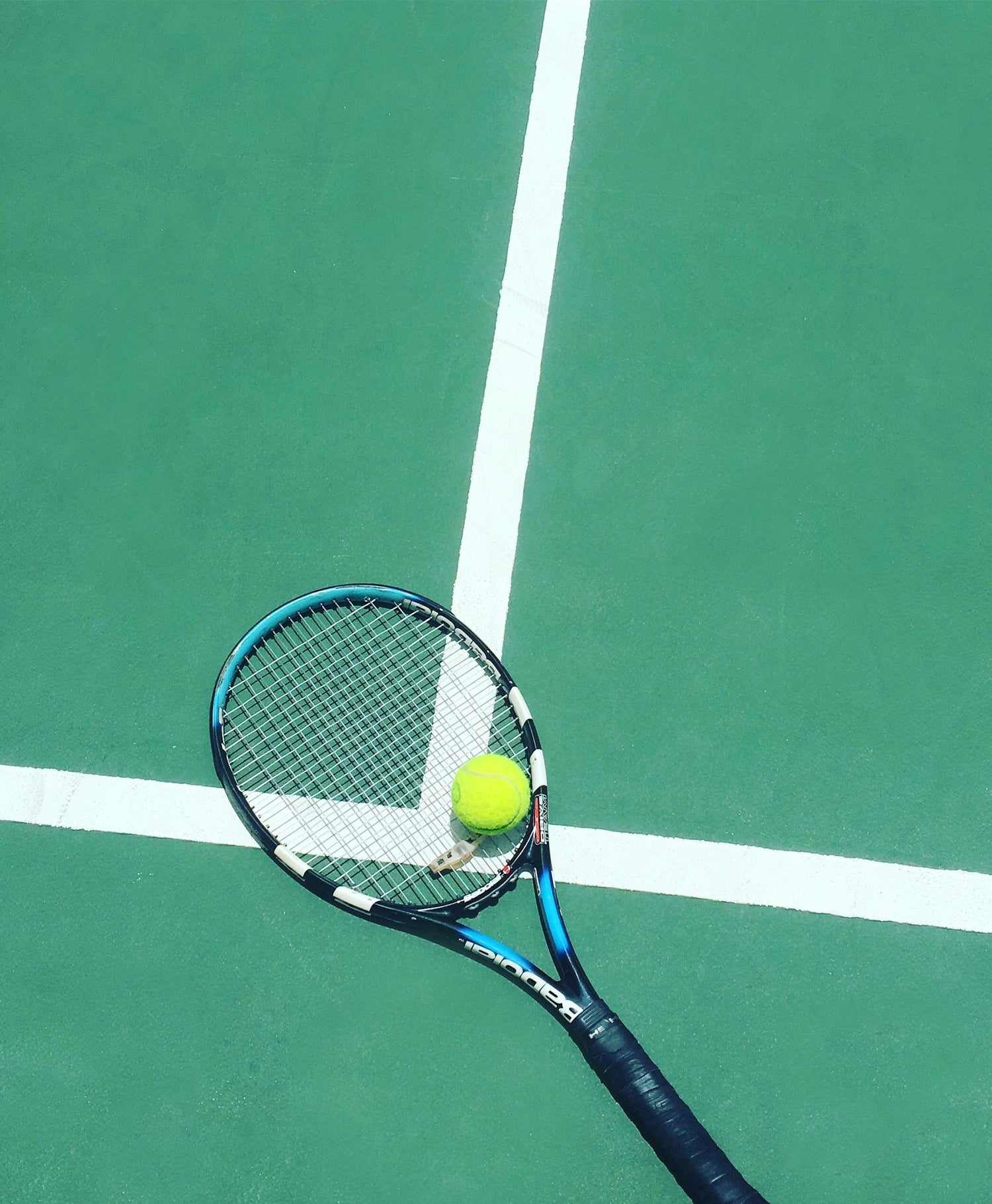 Raquete de tênis e bola sobre a superfície de saibro vermelho de uma quadra de tênis
