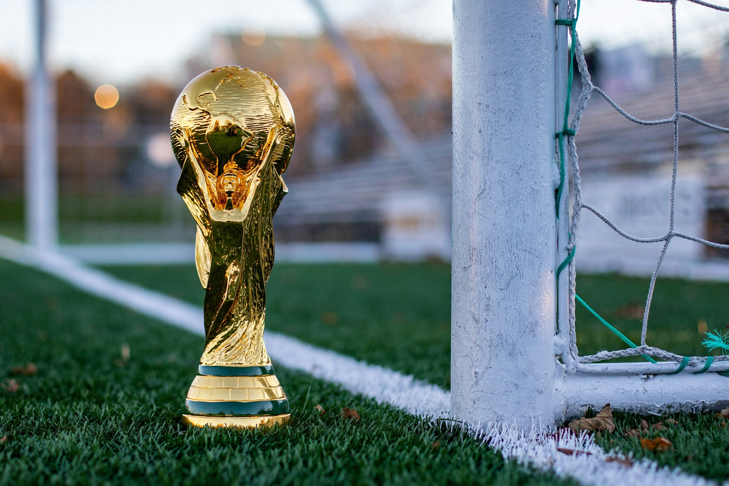 Troéu dourado da Copa do Mundo em um campo de futebol com gols ao fundo